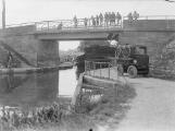 1 vue  - Canal, chemin de halage, embarcation et véhicule de traction sur pneus (halage électrique), enfants sur le pont. (ouvre la visionneuse)