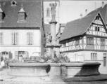 1 vue  - Ammerschwihr, place avec fontaine fleurie, en arrière plan l\'église. (ouvre la visionneuse)
