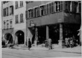 ouvrir dans la visionneuse : Rue des Grandes Arcades à hauteur du n°87, horlogerie E. Holtz, arcades et colonnes du passage, passants. [1940-1944].