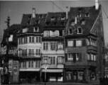 1 vue  - Place du Corbeau, îlot de maisons [détruites lors du bombardement du 11 août 1944], devanture de la société coopérative des cordonniers de Strasbourg et environs, cuirs et crépins, kiosque. [1940-1944]. (ouvre la visionneuse)