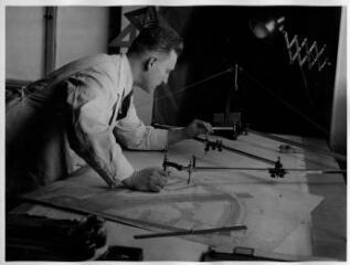 1 vue  - Géomètre entrain de reporter des annotations sur un plan parcellaire du Neudorf. [1940-1944]. (ouvre la visionneuse)